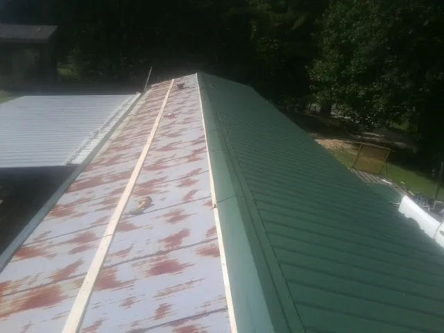 Old rusted panels beside newly installed green metal roofing — Wind Damage Roof Repair by Roofing Brothers in Stateline