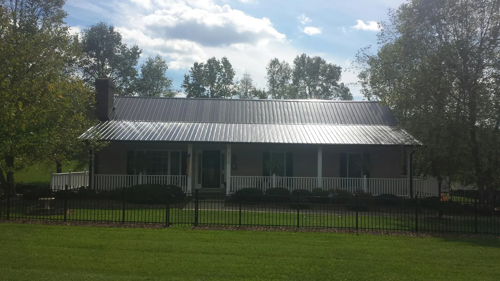 Gray metal roof on a brick ranch with a full width front porch — Gutter Guard Installation work by our crew in Stateline