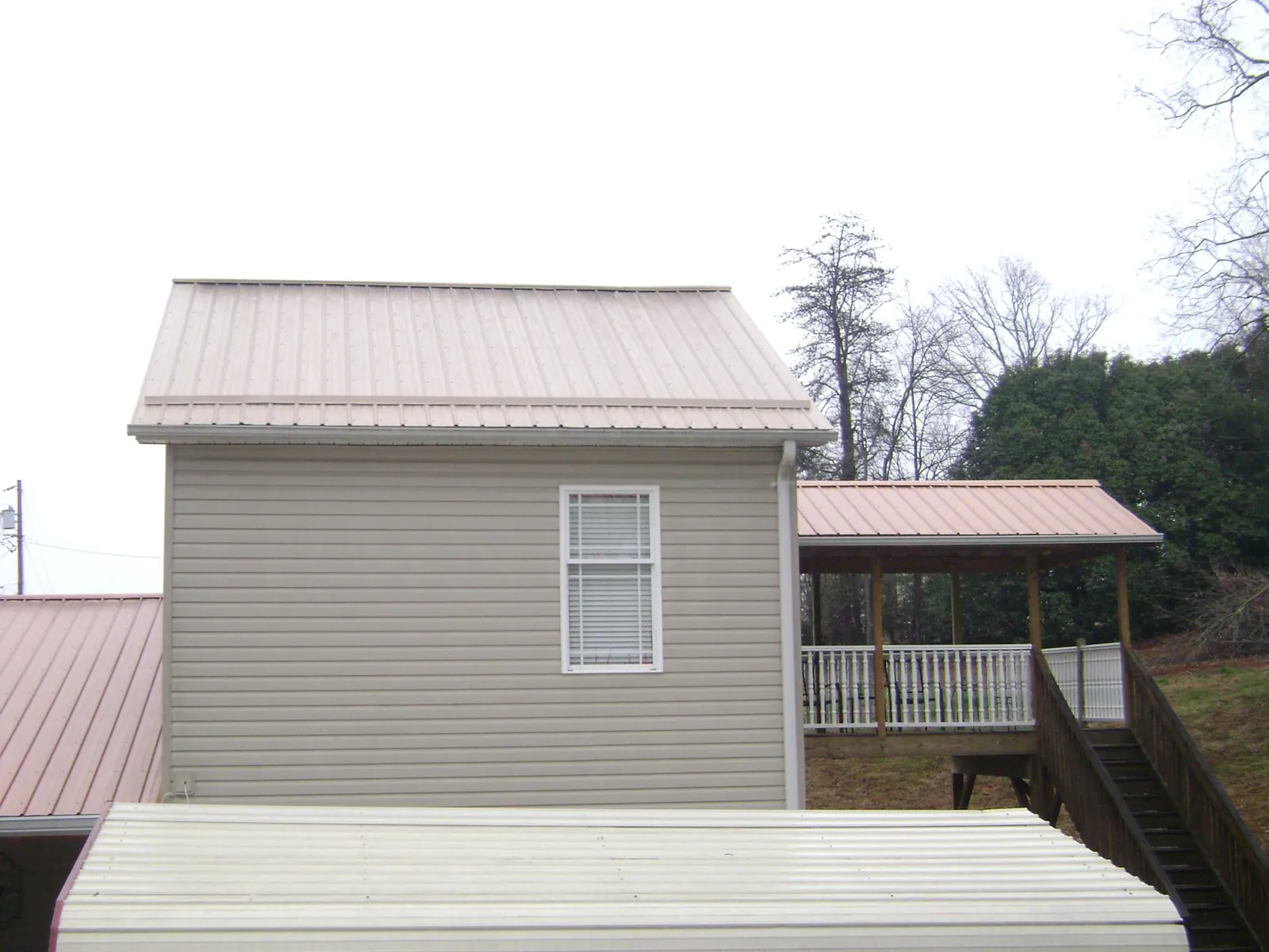 Tan metal roofs on a two story addition and attached porch, from a Roof Replacement job in Stateline