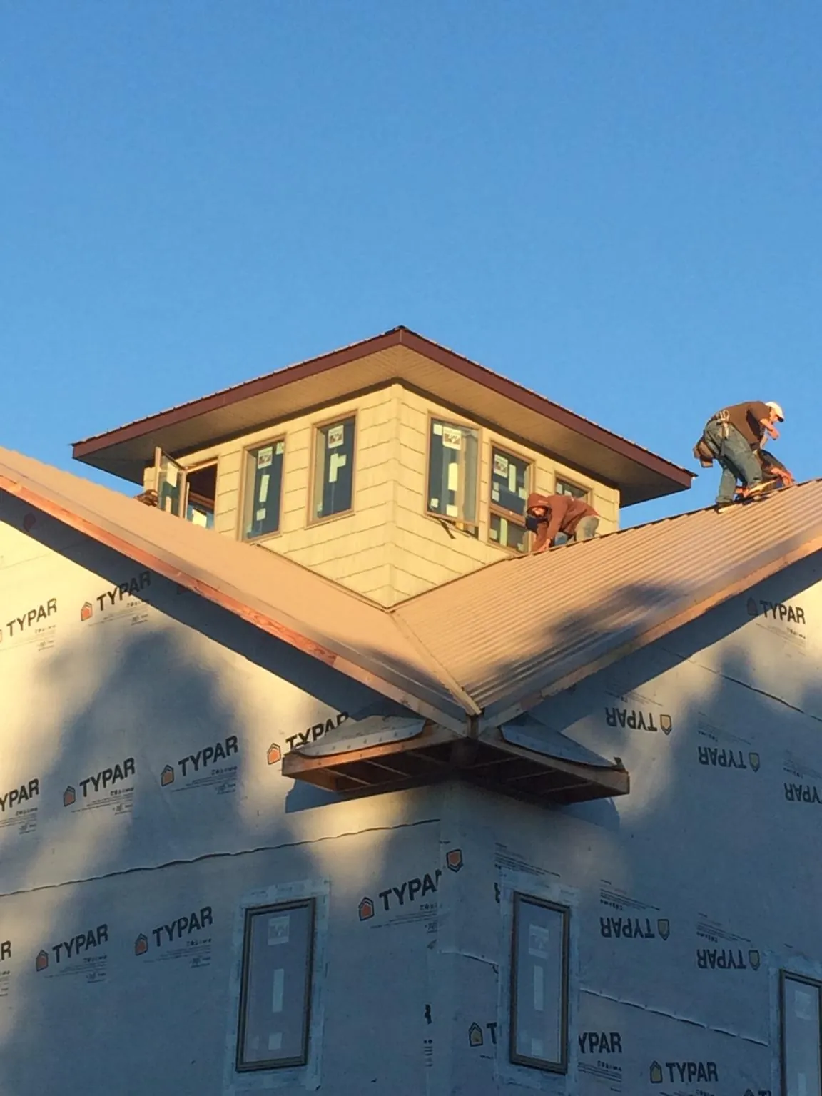 Roofers working around a rooftop cupola on a new metal roof at sunset — Roof Waterproofing in Stateline by Roofing Brothers
